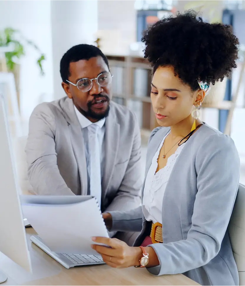 Two coworkers reviewing documents at a desk.