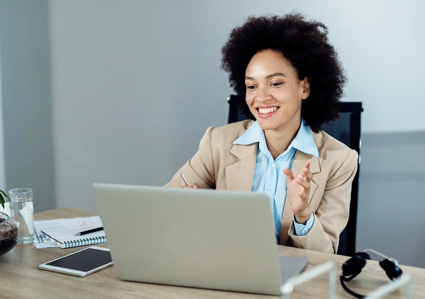Woman smiling during a video call at her desk.